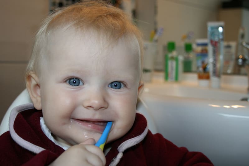Child learning correct brushing technique with a colourful toothbrush